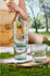 A drink bottle set featuring transparent recycled glass, stacked in three, alongside two glasses on a wooden tray.