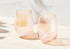 A set of two stemless wine glasses in soft pink, featuring a sleek design and a slight rim accent.