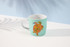 A teal coffee mug featuring a colourful turtle design, presented in a gift box.