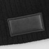 A black cable knit beanie featuring a textured patch. The material has a cosy, knitted appearance.
