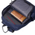 A navy backpack opens to reveal a striped interior, featuring a laptop, notebook, and a leather-bound journal.