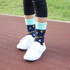 Colourful thermal socks featuring letters and shapes, with a mint green cuff, worn with white shoes.