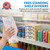 Hand holding a clear shelf divider beside neatly separated drinks and snack boxes on a retail shelf.