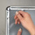 Hand replacing poster inside silver metal  wall-mounted snap frame with clear anti-glare cover for retail and business sign displays, CSF1-2030
