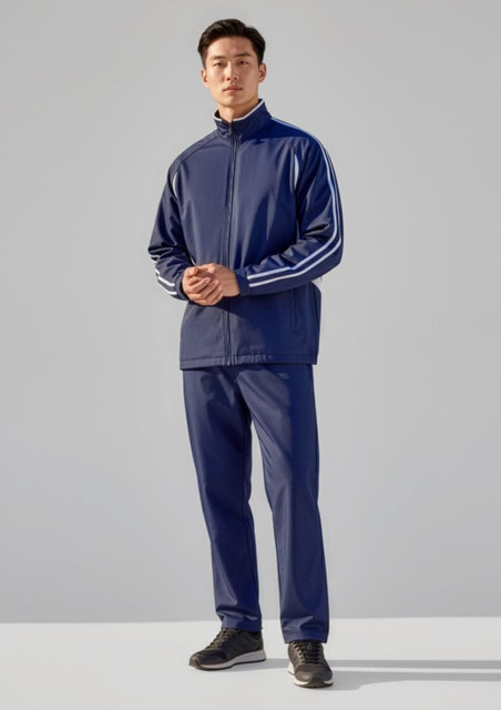 A model wearing unisex navy track pants paired with a matching zip-up jacket featuring white stripes.