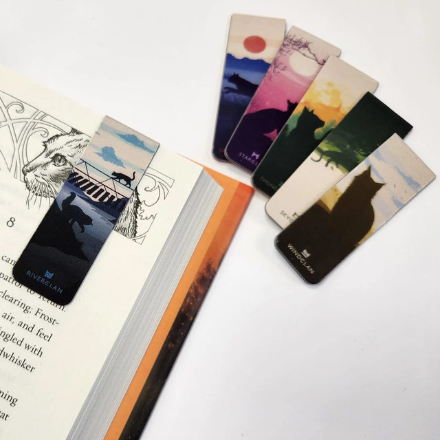 A set of colourful bookmarks featuring various designs and a fridge magnet resting on an open book.