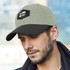 A cap in olive green with a black peak and patch, featuring a logo on the front.
