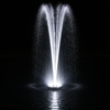 White LED-illuminated floating fountain at night creating a dramatic two-column water spray pattern that fans outward, with reflections visible on the dark pond surface below.