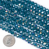 Close-up of crystal 5x6mm teal blue faceted rondelle beads with rainbow AB finish beside a dime for size reference.