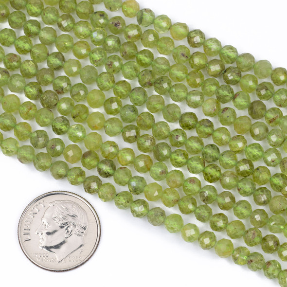 Cherry Tree Beads Peridot 4mm Faceted Round Beads shown next to a coin for size reference on a 15-inch strand of natural gemstone beads.