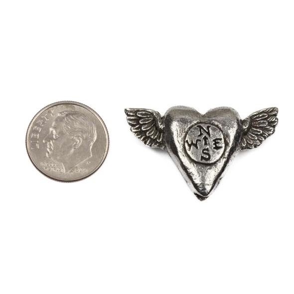 Green Girl Studios pewter 20x33mm 'Follow' flying heart bead with a compass design and wings, shown next to a dime for size reference, crafted from pewter for jewelry making.