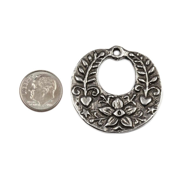 Green Girl Studios pewter approx. 37x38mm Large Round Floral Pendant, shown next to a dime for size reference, featuring intricate floral and heart details, crafted from pewter for jewelry making and statement pieces.