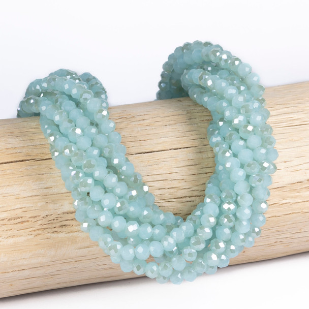 Cherry Tree Beads Crystal 5x6mm Faceted Rondelle, Opaque Aqua Blue Whisper beads draped on a wooden display, 15 inch strand for jewelry making.