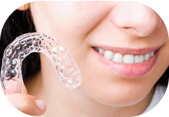 Person holding Instasmile Aligners next to face.