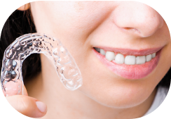 Person holding Instasmile Aligners next to face.
