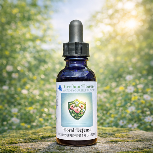 Bottle of Floral Defense flower essence placed on a stone in a bright, sunlit meadow filled with flowers.