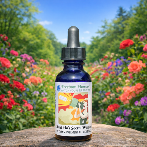Bottle of Aunt Flo’s Secret Weapon flower essence placed on a stone in a sunlit garden filled with colorful flowers.