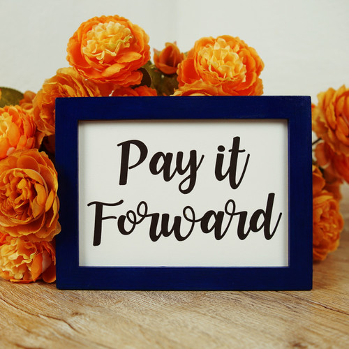 Framed picture of the words "pay it forward" surrounded by orange flowers