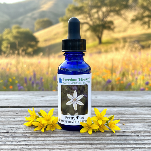 Pretty Face flower essence bottle with flowers around it and a sunlit hillside background.