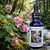Mountain Hollyhock flower essence bottle with Mountain Hollyhocks next to a stream in the background.