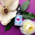 Bottle of Yarrow Shield Flower essence on a purple background with white rose and magnolia flower.