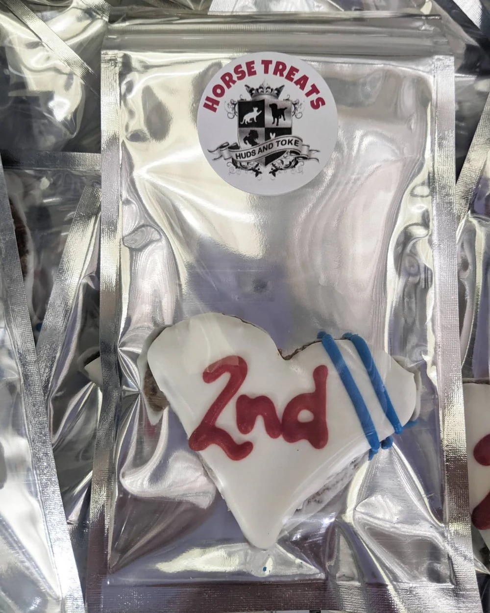 A white iced heart cookie marked 2nd in a sealed Huds and Toke horse treats bag