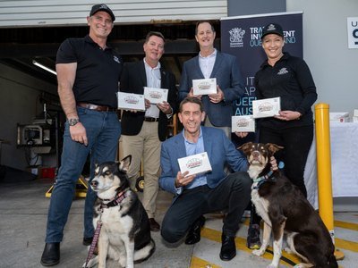 Russell and Emma Gibbons with Queensland Treasurer Cameron Dick and local MPs holding Krispy Kreme Doggie Doughnut boxes, with two dogs