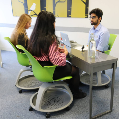 2 teenage girls sat a desk being interviewed by a south Asian interviewer during a Medicine MMI circuit