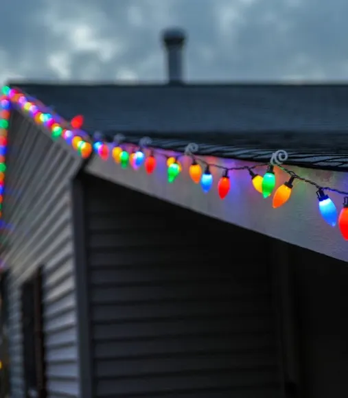 Multicolor C9 bulbs clipped along a roofline