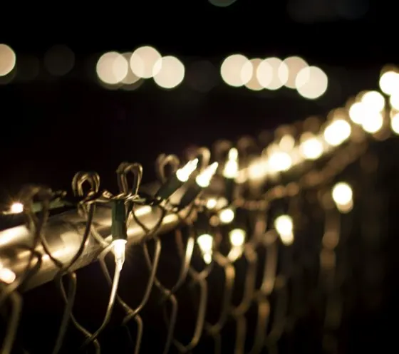 Warm white mini light strings on a fence line at night