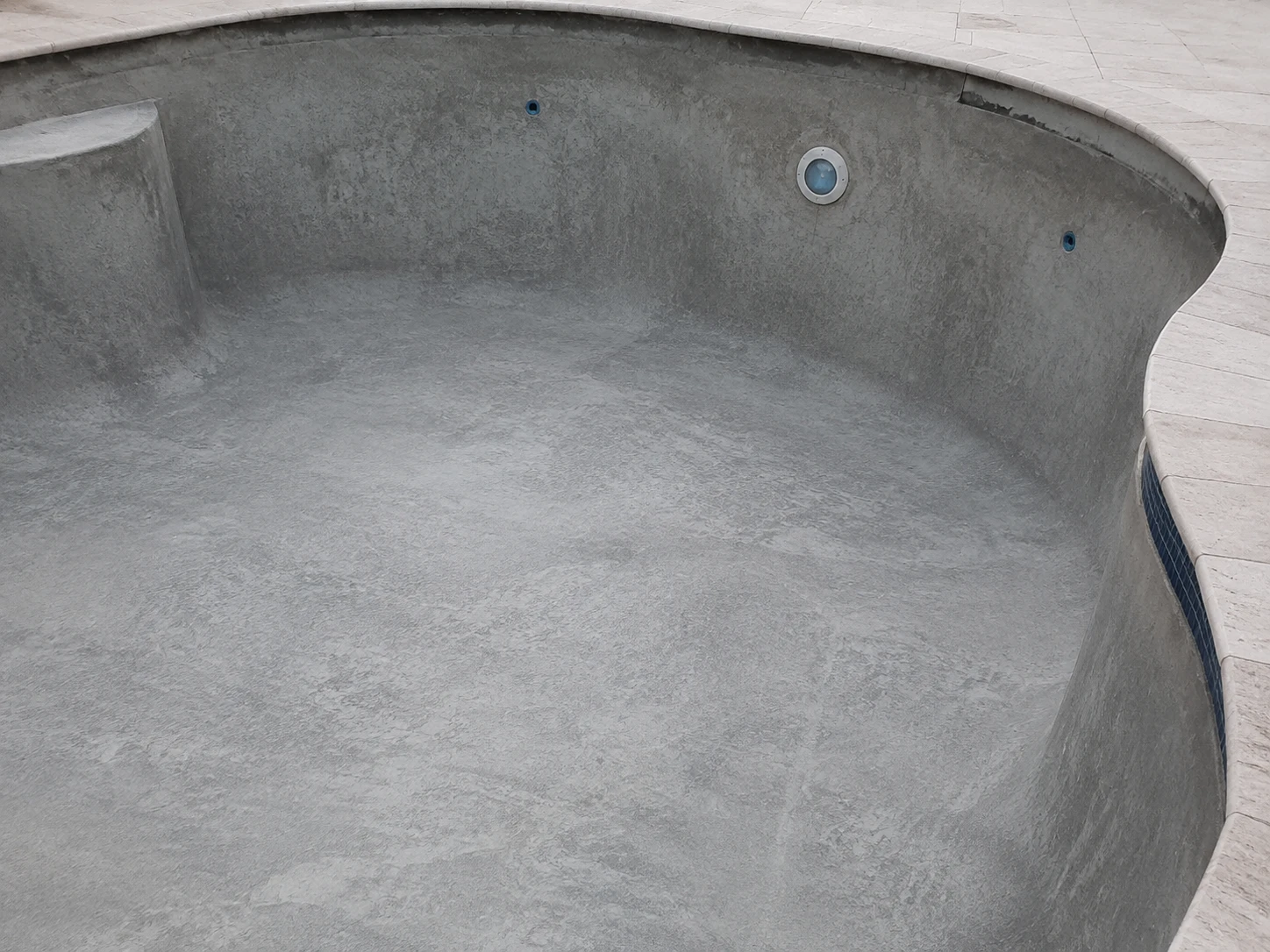 Bare uncoated concrete swimming pool surface