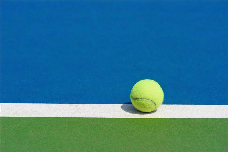 Durable blue and court-green outdoor acrylic sport surface with a tennis ball on the boundary line