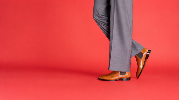 Person wearing custom tan Chelsea boots and grey trousers