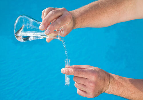 Man pouring water out of a flask into a test tube