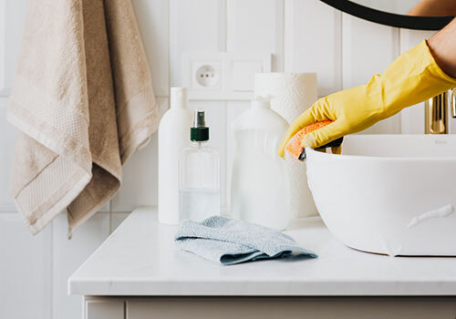 Gloved hand wiping the edge of a bathroom sink