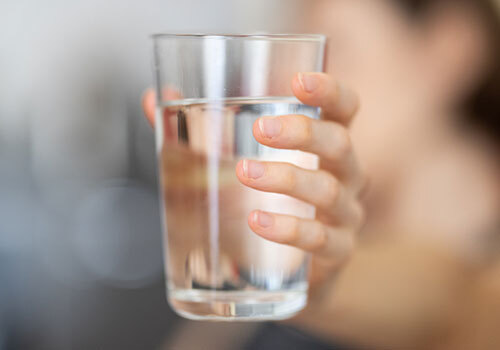 Woman's outstretched hand holding a glass of water