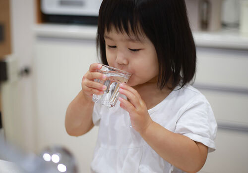 Little girl drinking from a glass of water