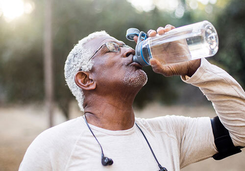 Old runner drinking from a water bottle