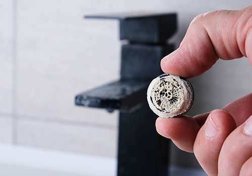 Close-up of a man holding limescale build-up on a tap