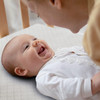 Happy baby smiling at mom while laying on a Yeti crib mattress by ergo-pedic.