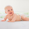 Healthy baby in a diaper laying on a firm and comfortable crib mattress with coil support by ergoBean.