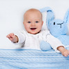 Happy baby with favorite blue toy on a ergoBean Basics Mini5 Dual -Stage Breathable Mini Crib Mattress.