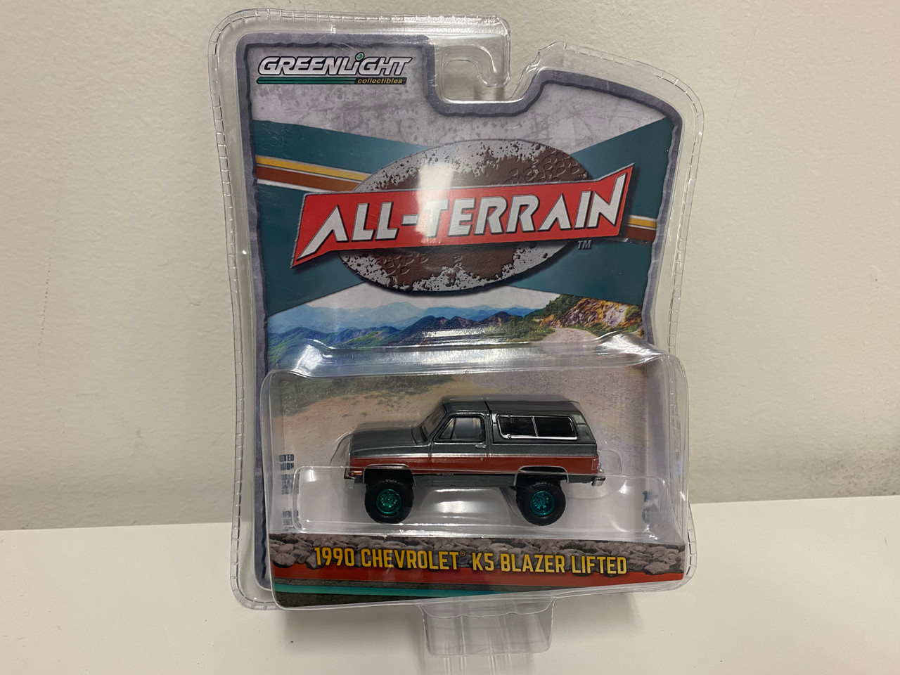 CHASE CAR 1/64 Greenlight 1990 Chevrolet K5 Blazer 1500 Lifted Gray Metallic with Fire Red and Black Stripes Diecast Car Model