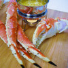 Giant king crab legs & claw on a wood cutting board with a butter warmer full of melted butter.
