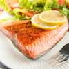 Just roasted, Alaska sockeye salmon tail portion with lemon slices and salad.
