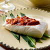 A cooked Alaska halibut fillet portion with a thick red sauce on top.