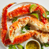 Giant Alaska king crab legs and claw on plate with lime wedges.