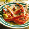 Split king crab legs in a gold-rimmed bowl with butter sauce poured over top.