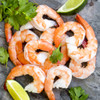 A pile of shelled cooked shrimp with lime wedges nearby.