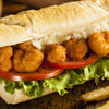 A scrumptious golden alehouse shrimp hoagie with lettuce, tomatoes, & mayo.